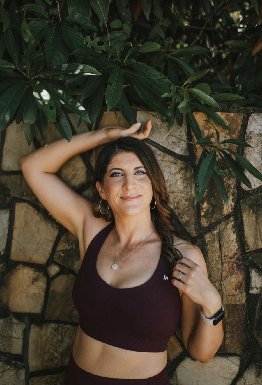A UNLMTD woman smiling under green leaves